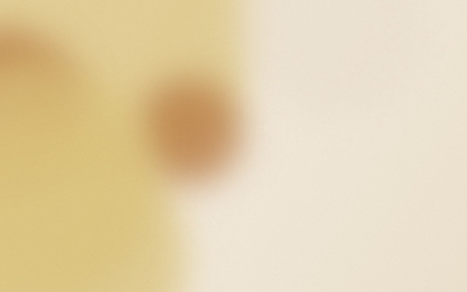A blurred close-up of a pale yellow background with a darker rounded shape.